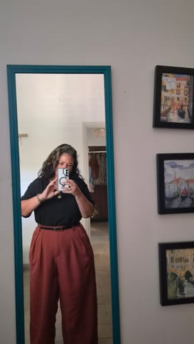 Reviewer's mirror selfie wearing high-waisted hamra-colored Ram trousers with a black shirt.