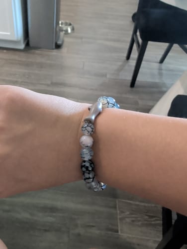 Reviewer's arm wearing the Voyage Bracelet with a grey shark charm and patterned beads.