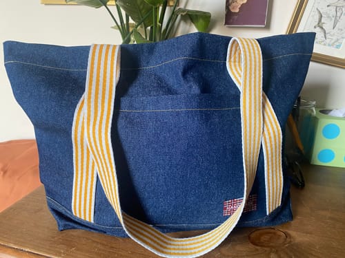Customer's dark blue washed denim fabric sewn into a tote bag with yellow and white striped handles.