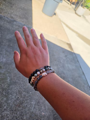 Customer's wrist wearing three stacked Voyage Bracelets featuring small animal charms and multi-colored beads.