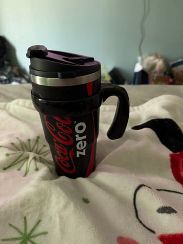Customer's black Coca-Cola Coke Zero To-Go Buddy tumbler with a handle, resting on a patterned blanket.