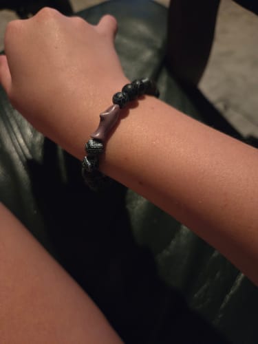 Customer's dark Voyage Bracelet with a charm on their wrist.