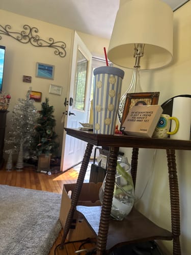 Customer's striped To-Go Buddy tumbler with polka dots, sitting on a side table in a cozy room.
