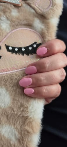 Kundenfoto der Lovely Pink UV Gel Nagelfolien auf Fingernägeln, gehalten vor einem kuscheligen, gemusterten Stoff.