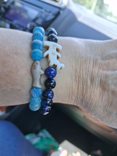 Customer's two Voyage Bracelets worn on wrist, featuring blue beads and a light-colored shark charm.