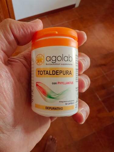 Customer's hand holding a white TotalDepura bottle with an orange lid and nutritional supplement branding.
