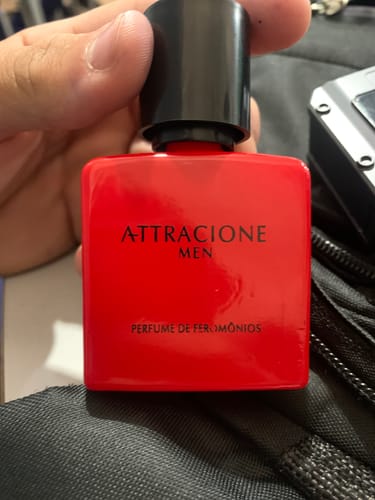 Customer's Attracione Men perfume bottle with a bright red square container held in hand.
