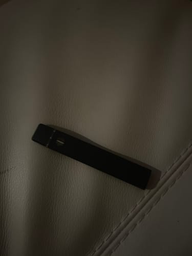 Customer's black THCA Vape lying flat on a textured, light-colored surface.