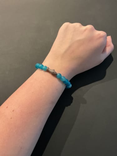 Reviewer's arm wearing a blue Voyage Bracelet featuring a shark charm.