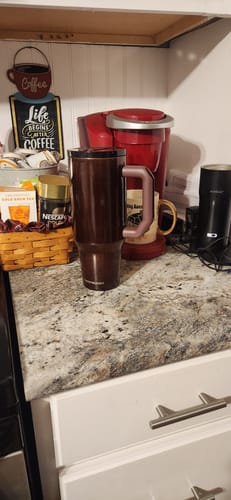 Customer's brown Thicc Buddy mug placed on a granite kitchen counter next to a coffee machine.