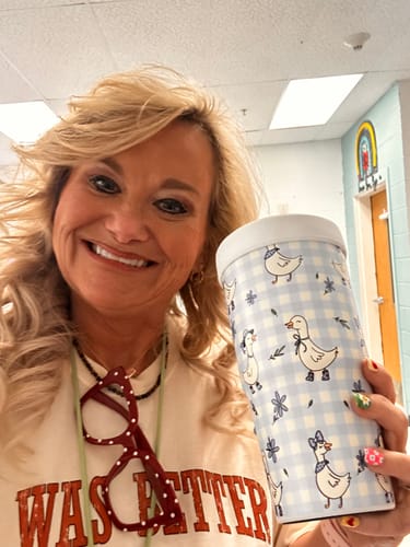 Customer's smiling selfie holding a light blue To-Go Buddy tumbler patterned with cute little geese.