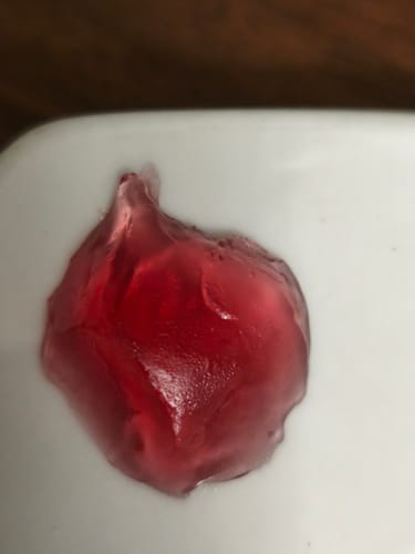 Reviewer's red THC Spacejellies 2.0 gummy showing an irregular, misshapen appearance on a white surface.