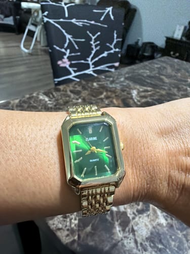 Reviewer's wrist wearing the gold Claire De Mains watch with a vibrant green face.