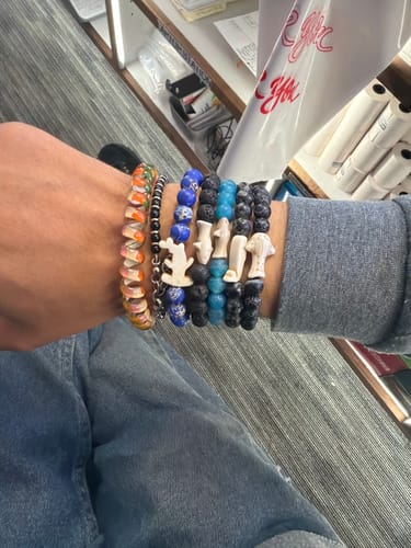 Customer's wrist wearing multiple Voyage Bracelets including shark and animal charm styles.
