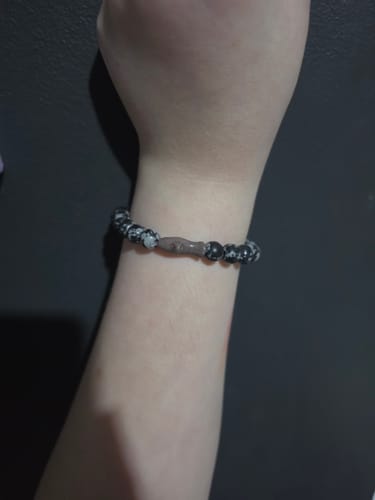 Reviewer's arm wearing the speckled-pattern Voyage Bracelet with a central shark-shaped charm.