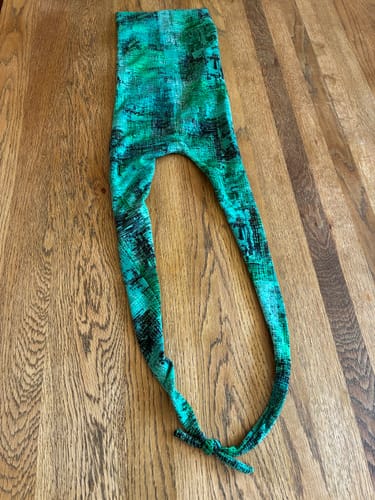 Customer's green abstract print head cover made from Glitch Grid jersey fabric, laid flat on a wooden surface.