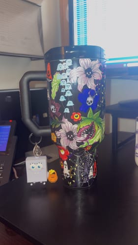 Reviewer's Toxic Bloom Thicc Buddy mug with a colorful ghost and flower pattern and a SpongeBob keychain on the handle.