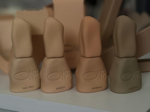 Customer's Glaze Top shown in a lineup of four beige nail care bottles on a white surface.