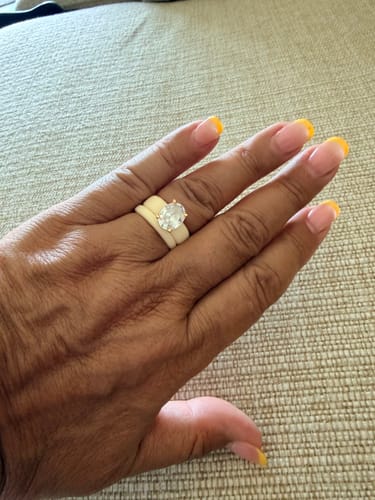 Customer's GlowStone Silicone Ring set with an oval-cut stone on a hand with yellow nail polish.
