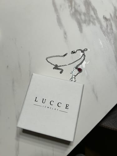 Customer's Lucce Signature Necklace resting on a white gift box against a marble surface.