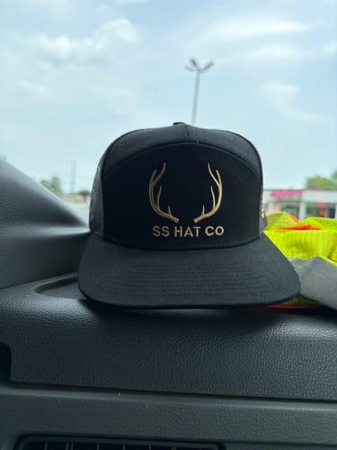 Customer's Hat of the Month Crew cap with a black mesh back and embroidered deer antler logo, sitting in a vehicle.