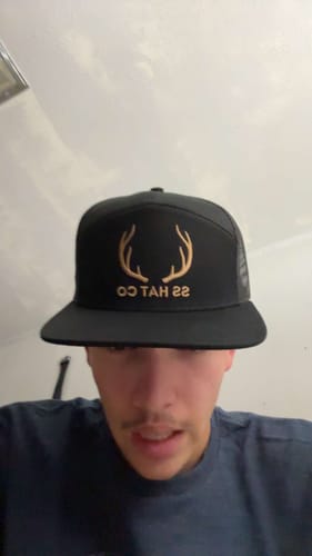 Customer's Hat of the Month Crew hat, black with gold antler logo, worn by a person.