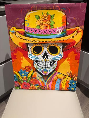 Customer's completed Day of the Dead paint-by-numbers kit featuring a colorful skull wearing a yellow hat.