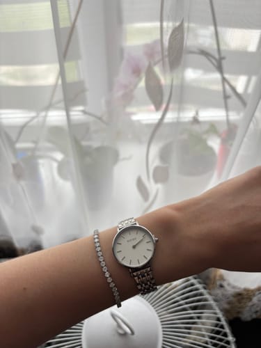 Customer's silver Ruby Petite watch with a white dial on a wrist next to a sparkling tennis bracelet