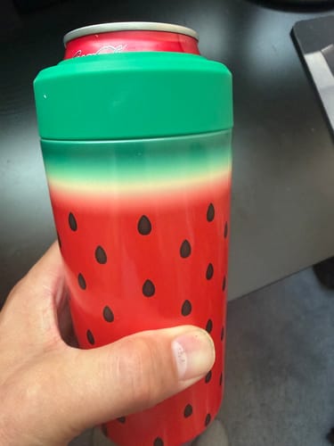 Customer's hand holding a red and green watermelon-patterned Mystery Universal Buddy with a beverage can inside.