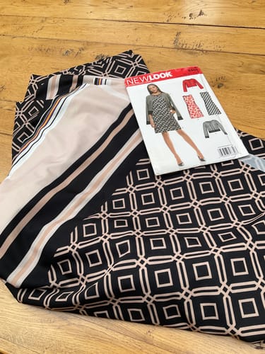 Customer's Diamond Grid Jersey Fabric laid on wood, featuring a diamond print and a sewing pattern placed on top.