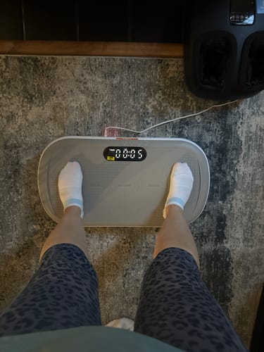 Customer's feet standing on the gray CV40 Vibration Plate, with the LED timer display showing five seconds elapsed.