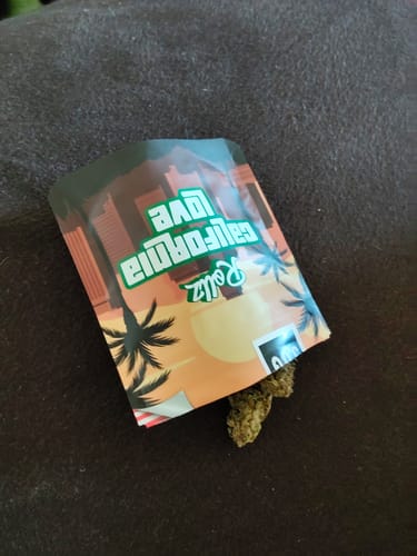 Customer's California Love THC-A flower packaging with a visible, dense green bud resting on a dark surface.