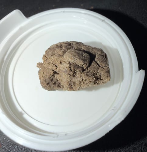 Customer's THC-A 60% Hash Plasma shown as a dense, brown chunk of pressed resin in a white container lid.
