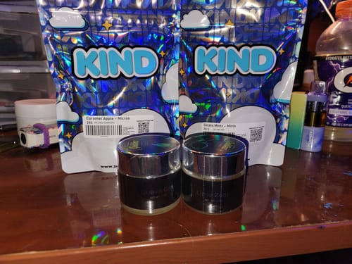 Customer's KIND Gelato Mintz and Caramel Apple shiny holographic bags with two small dark jars sitting on a desk
