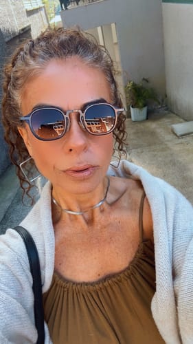 Cliente usando Óculos de Sol Bali com armação metálica e lentes escuras em ambiente externo.