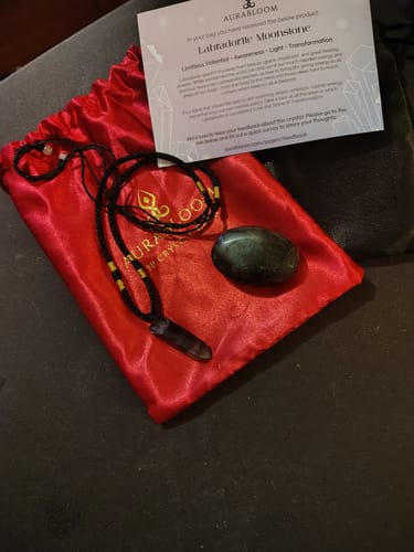 Customer's VIP Crystal Club palm stone and crystal necklace displayed on a red bag with an information card.