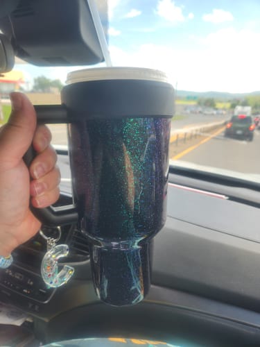 Customer's dark Mermaid Thicc Buddy mug held in a car, showing the sparkly finish and a decorative letter charm.