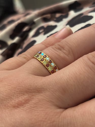 Customer's hand wearing two gold-plated Eterna Birthstone Rings stacked, featuring colorful cubic zirconia stones.