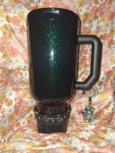 Customer's Thicc Buddy 50oz Mermaid mug with dark glitter finish and handle, shown against a floral patterned background.