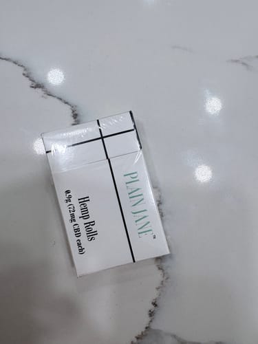 Customer's white pack of Plain Jane Hemp Filtered Pre-Rolls resting on a marble surface.