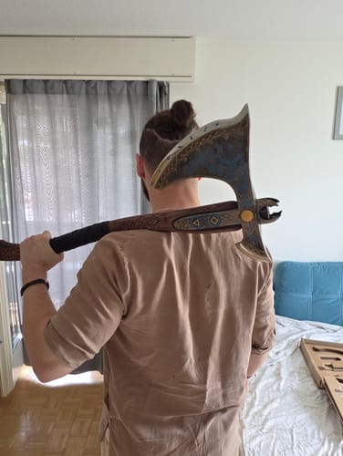 Customer's Leviathan Kratos axe held over the shoulder, showing the engraved wooden handle and detailed axe head.