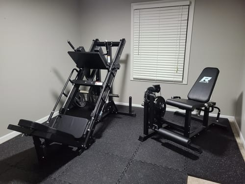 Customer's sturdy black gym equipment installed in a home gym with rubber flooring and window blinds.