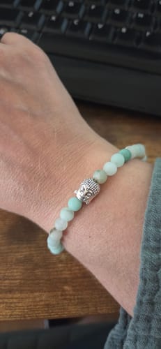 Customer's hand wearing the delicate green Amazonite Buddha bracelet from the AuraBloom subscription box.