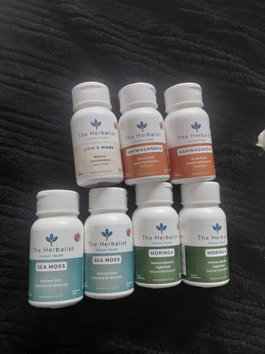 Customer's Lion's Mane 60/120 Capsules bottles displayed alongside other Herbalist supplement bottles on a dark surface.