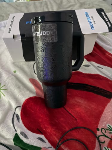 Customer's black lace patterned Thicc Buddy 50oz tumbler in front of its product box on a patterned blanket.