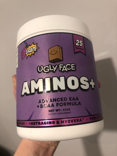 Reviewer's hand holding a purple grape-flavored UGLYFACE AMINOS+ supplement jar.
