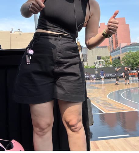Customer's black Utility Shorts worn by a person, featuring a high-waisted fit while standing on an outdoor court.