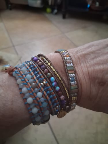 Customer's hand wearing three layered Square Opal Healing Wrap bracelets with colorful stone and leather details.