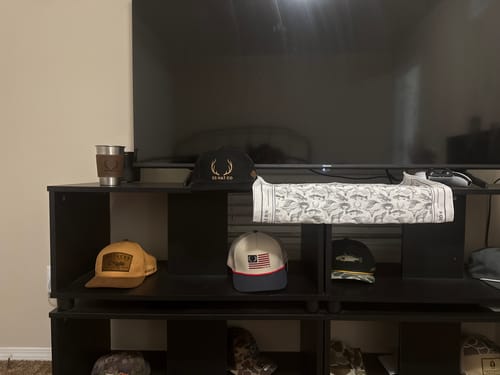 Customer's Hat of the Month collection, featuring several different styles displayed on shelves under a television.