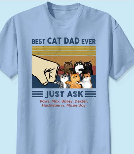 Customer's light blue personalized Cat Dad shirt featuring six cats fist-bumping a human hand, with their names printed.